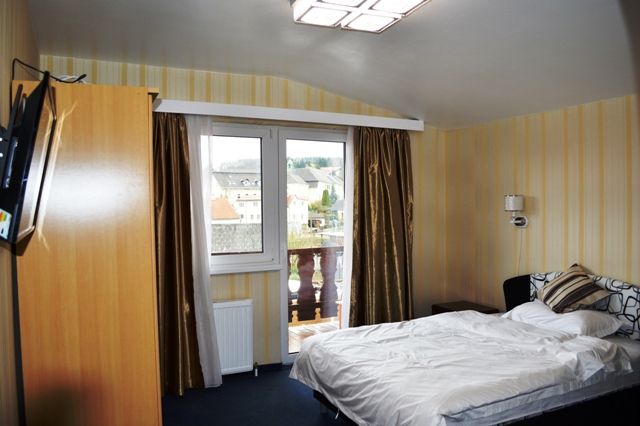 Ein Hotelzimmer mit Doppelbett, Fenster mit Vorhängen und Blick auf Gebäude im Freien.