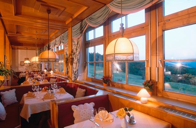 Gemütliches Restaurant mit Holzeinrichtung und großen Fenstern mit Blick auf die Landschaft.