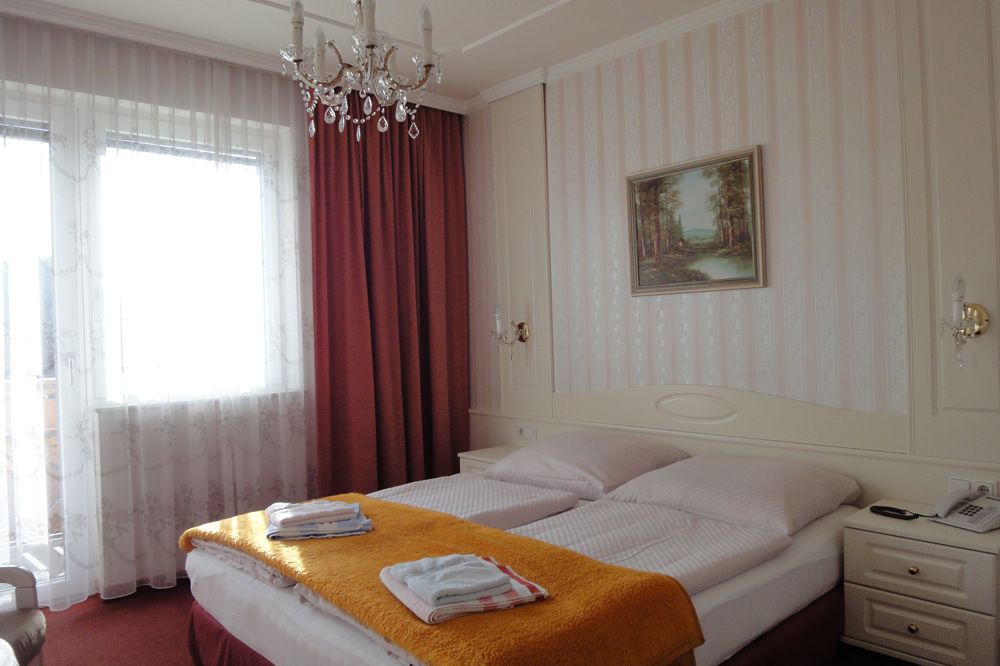 Hotelzimmer mit Doppelbett, Kronleuchter und Gemälde an der Wand.